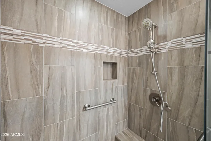 Scottsdale bathroom with walk-in stall shower featuring large-format tile, accent strip, and built-in niche. Clean, updated design enhances daily comfort.