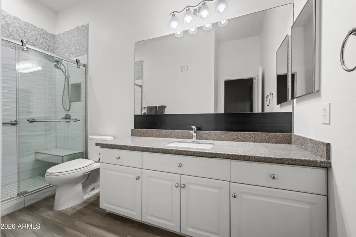 Scottsdale ensuite bathroom featuring a spacious dual vanity, granite countertops, and updated lighting. Walk-in glass shower and modern finishes enhance comfort and functionality.