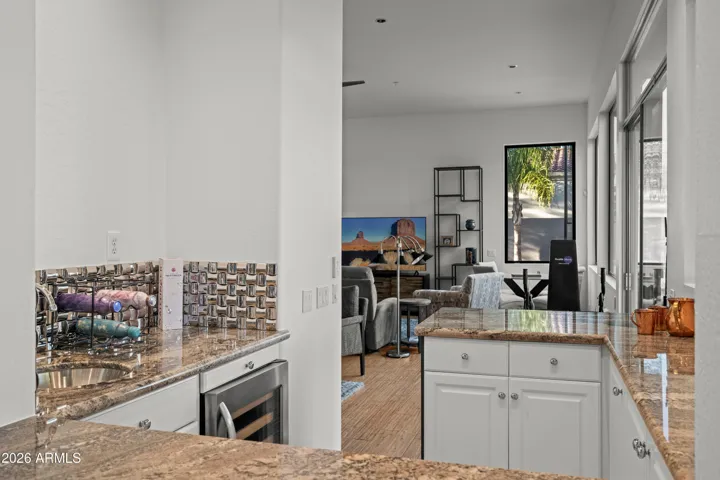 Open Scottsdale living and entertaining area with built-in bar, granite counters, and seamless layout. Perfect for hosting with easy access to indoor and outdoor spaces.