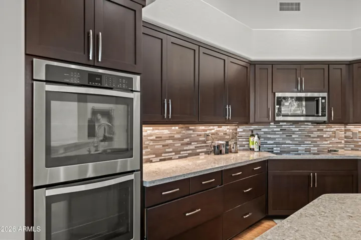 Updated Scottsdale kitchen with quartz countertops, custom cabinetry, and stainless steel appliances. Stylish backsplash and modern finishes enhance functionality and design.