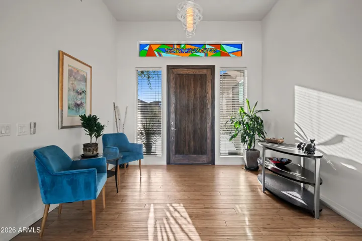 Spacious Scottsdale foyer featuring a custom wood front door, modern lighting, and stylish finishes. Natural light and clean design create a welcoming first impression.