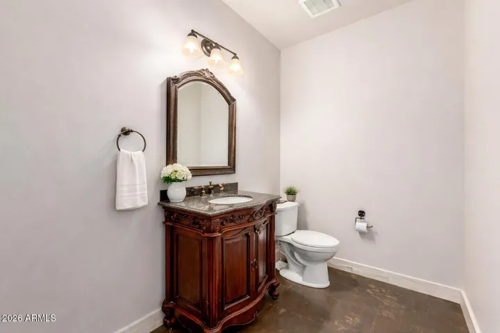 Elegant powder room featuring a classic vanity, detailed woodwork, and warm lighting.