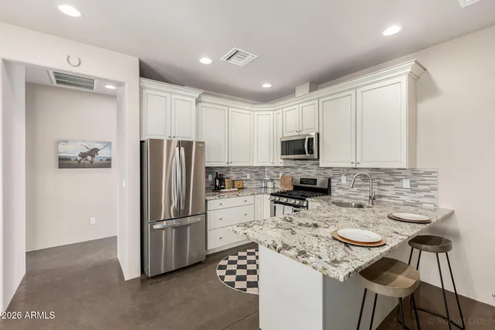 Stylish kitchen with white cabinetry, granite countertops, and stainless steel appliances.