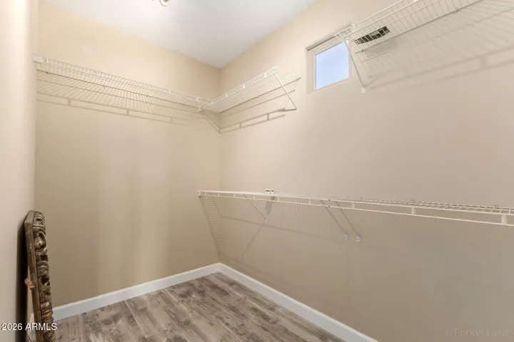 Well-designed walk-in closet featuring natural light and wraparound shelving.