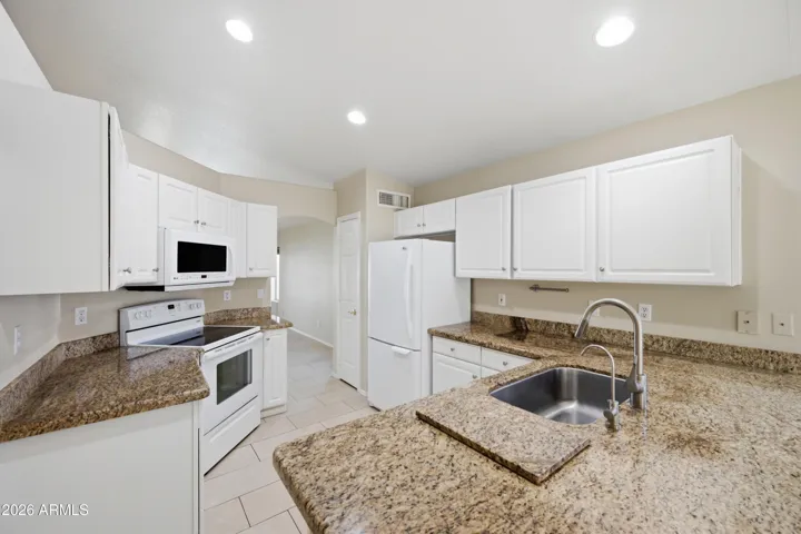 This Kitchen is the heart of the home. Neutral slab Granite counters, breakfast bar, pantry and white cabinets.