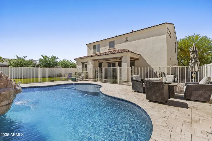 Large backyard with pool, travertine surround, large grassy area and more.