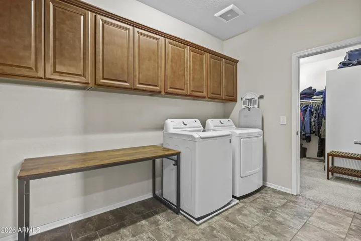 Upstairs laundry with cabinets, folding table and access to the primary closet