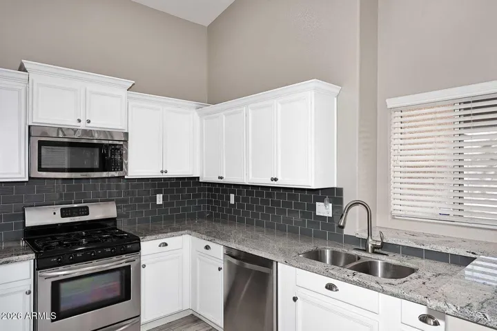Coordinated backsplash ties white cabinets, stainless steel appliances and granite countertop together.