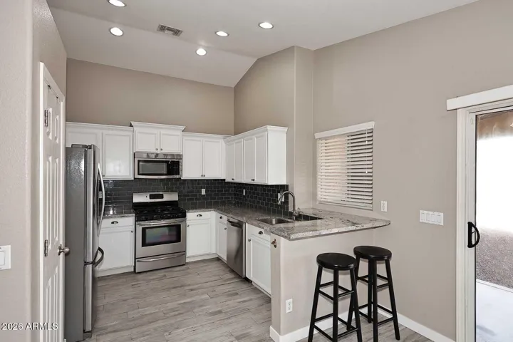 Kitchen with SS appliances, gas stove and granite countertops. Steps to eat-in kitchen. Sliding door to the pool/tv patio area. Window over the sink looks out to the pool.