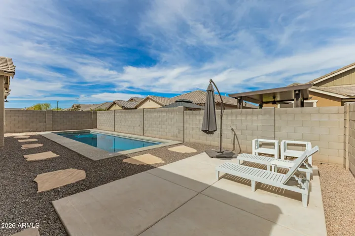 Inviting backyard featuring a private pool, spacious patio, and lounge seating, perfect for outdoor relaxation and entertaining in this Surprise home.