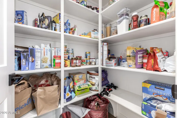 Large walk-in pantry with ample shelving and storage space, perfect for organizing groceries and kitchen essentials in this well-designed Surprise home.