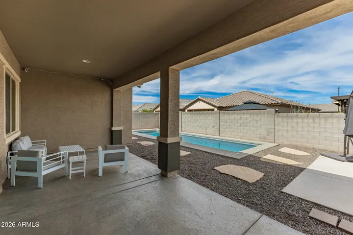 Covered patio perfect for outdoor living, featuring shaded seating area and easy access to the backyard in this Surprise home.