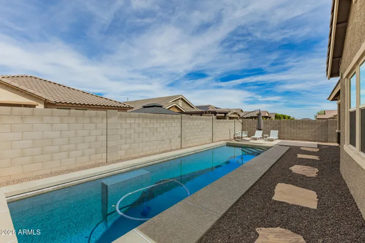 Beautiful backyard retreat featuring a sparkling pool, patio seating, and privacy wall, perfect for relaxing or entertaining in Surprise.