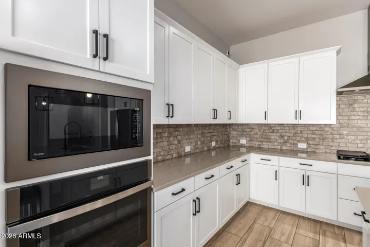 Spacious kitchen with built-in oven and microwave, extensive cabinetry, quartz counters, and functional layout designed for cooking, storage, and everyday living in Surprise.