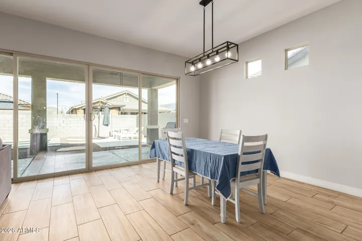 \Bright dining space with modern lighting and direct access to the covered patio, ideal for indoor-outdoor dining and entertaining in this Surprise home.