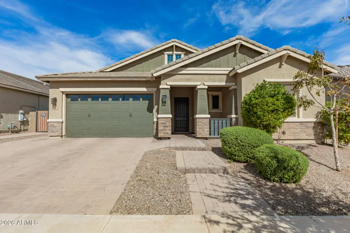 Inviting exterior of this Surprise home with desert landscaping, paver driveway, and a 4-car garage, offering great curb appeal and low-maintenance design.