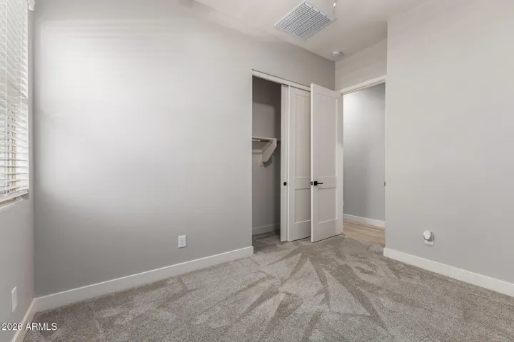 Functional bedroom featuring plush carpet, closet space, and convenient access to hallway, designed for everyday comfort in this Surprise home.