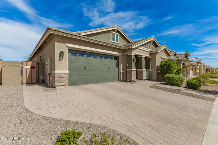 Beautiful front exterior showcasing extended paver driveway and spacious 4-car garage, ideal for extra parking, storage, and convenience in Surprise.