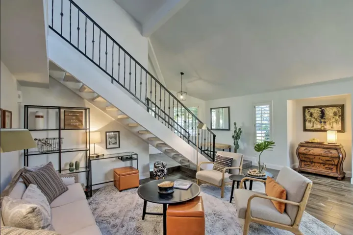 The living room features a desk tucked under the open staircase.