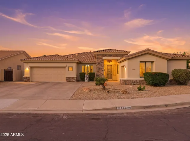 Evening photo featuring the illuminated entryway and stone architectural details of this Goodyear home. The well-designed exterior lighting enhances the property’s curb appeal and welcoming presence.
