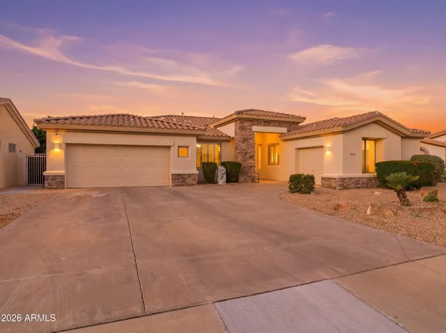 Twilight exterior photo capturing the warm curb appeal of this Goodyear home. The stone accents, desert landscaping, and inviting entryway combine to create a striking first impression at sunset.
