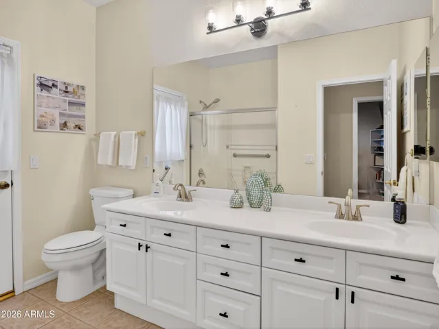 Spacious bathroom featuring a dual sink vanity with abundant cabinetry, large mirror, and bright lighting. The clean finishes and generous counter space add functionality and style to this Goodyear home.