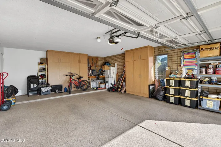 Side entry garage with work bench, storage cabinets, and epoxy flooring