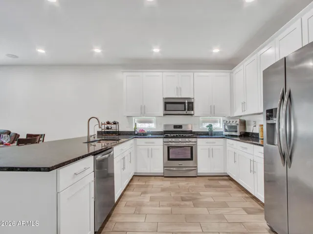 Kitchen with stainless steel appliances, gas range, and black granite counter top