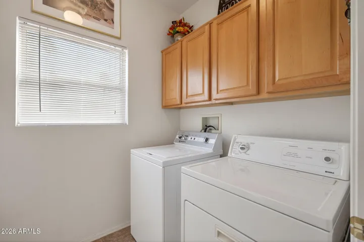 The laundry room features cabinets and lots of room for your ironing board.
