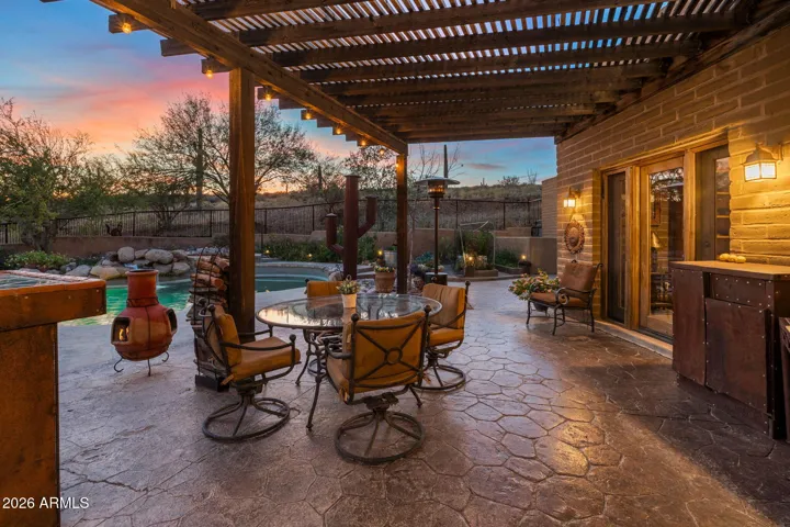 Warmly lit covered patio overlooking the pool, blending indoor-outdoor living with scenic twilight views.