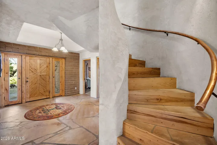 Architectural curved staircase with wood treads and custom railing, adding visual interest and character to the entry.