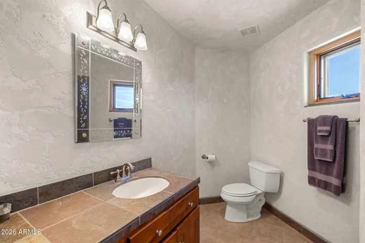 Convenient guest bathroom with stone countertop vanity and textured wall finishes.