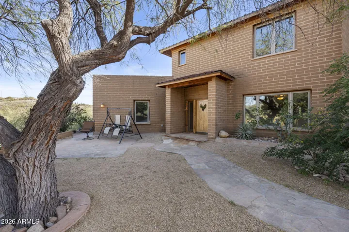 Private courtyard entry with mature desert landscaping and a shaded sitting area, creating a peaceful arrival experience.