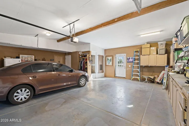 Spacious four-car garage with epoxy-style concrete flooring, built-in cabinetry, overhead storage, and additional workspace for tools or hobbies.