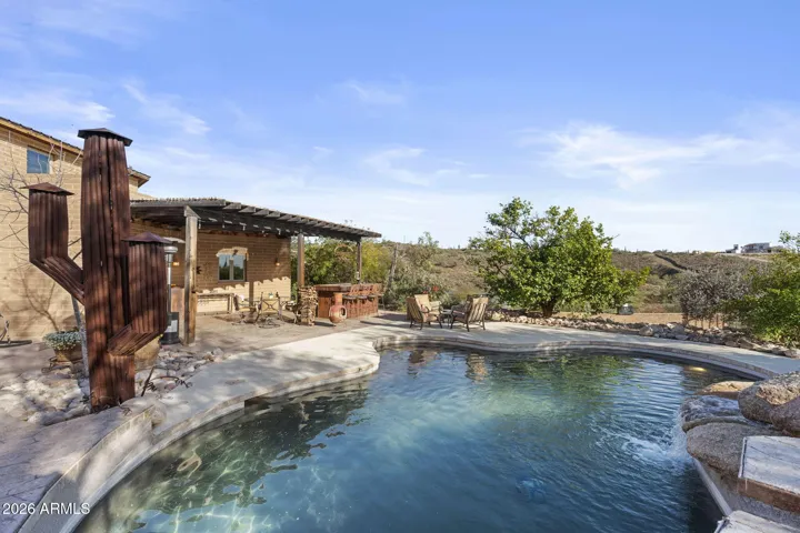 Freeform pool with natural rock accents and surrounding patio space, positioned to capture scenic desert and hillside views.