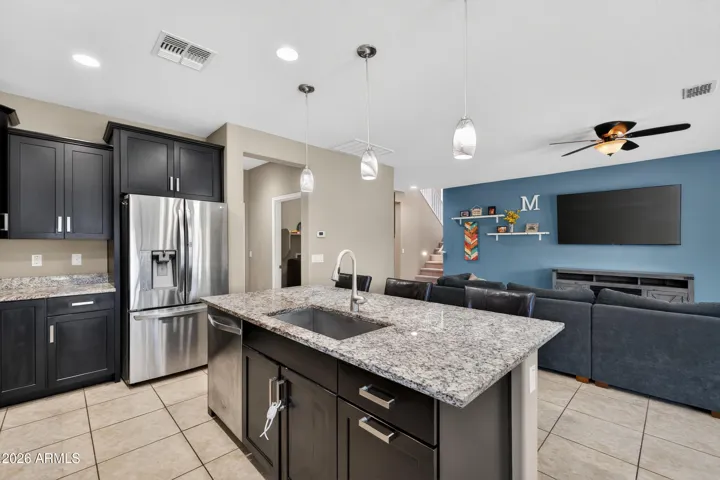 Gourmet Eat-in Kitchen Showcases 42" Expresso Staggered Cabinets with Pullouts, Granite Counters, Recessed lighting, Walk-In Pantry, Pendant Lights, Canopy Hood, Wall Oven/Microwave, 5 Burner Gas Cooktop, Single Bowl Sink, and a Center Island with Breakfast Bar.