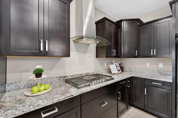 Gourmet Eat-in Kitchen Showcases 42" Expresso Staggered Cabinets with Pullouts, Granite Counters, Recessed lighting, Walk-In Pantry, Pendant Lights, Canopy Hood, Wall Oven/Microwave, 5 Burner Gas Cooktop, Single Bowl Sink, and a Center Island with Breakfast Bar.