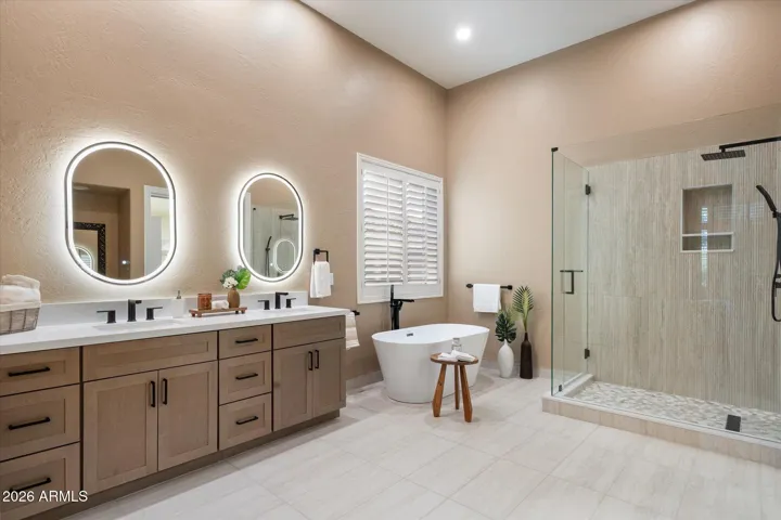 Sophisticated primary bath with soaking tub is fully remodeled from the flooring and new shower to the custom cabinets with lighted mirrors and new light fixtures.