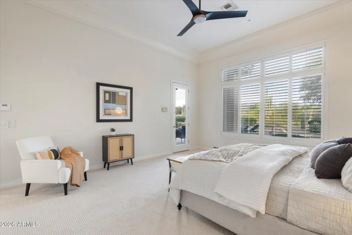 Remodeled primary bedroom features new paint, carpet, and ceiling fan and an exit out to your resort-style backyard oasis and stunning mountain, desert, and golf course views