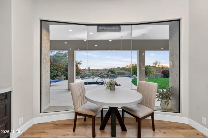 Cozy breakfast nook with large frameless windows offering scenic views of the pool and outdoor living space, enhancing Scottsdale indoor-outdoor lifestyle.