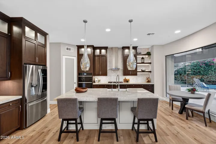 Open Scottsdale kitchen with large island, designer pendant lighting, stainless steel appliances, and seamless connection to living areas.
