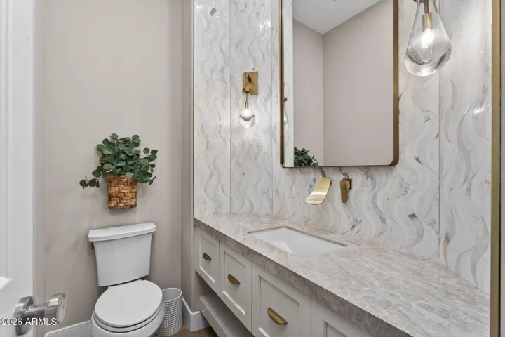 Updated Scottsdale powder room with modern vanity, porcelain slab countertops, designer backsplash, and elegant lighting fixtures for a refined look.