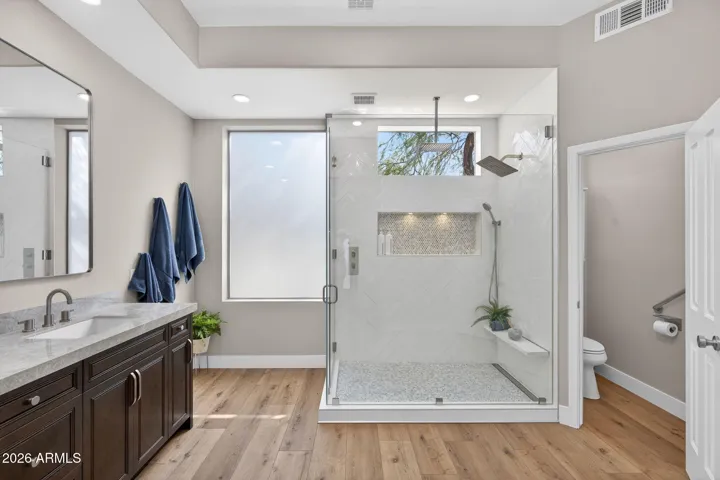 Modern Scottsdale bathroom with a spacious glass walk-in shower, custom tile work, and built-in niche, showcasing luxury upgrades and thoughtful design.