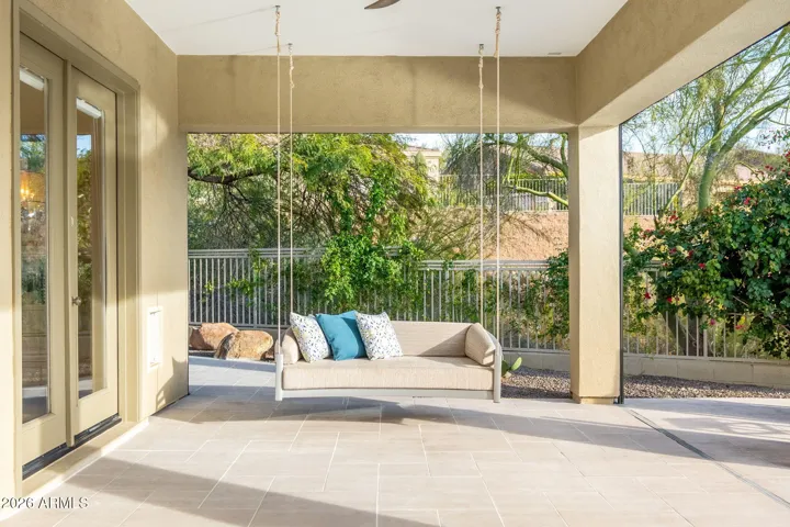 Inviting Scottsdale patio with hanging swing bench, tiled flooring, and tranquil views of landscaped backyard and outdoor living space.