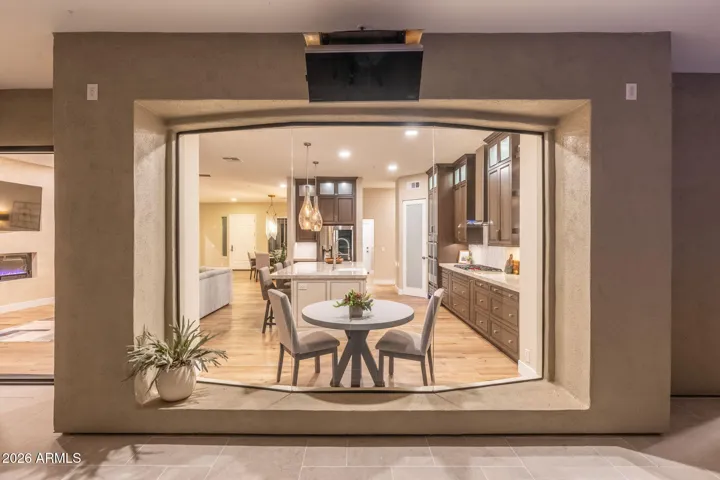 Unique architectural window showcasing the chef’s kitchen with island seating, custom cabinetry, and modern lighting, blending indoor elegance with outdoor views.