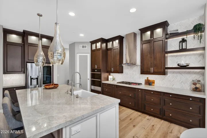 Elegant Scottsdale kitchen featuring rich wood cabinetry, porcelain countertops, stainless steel appliances, and designer backsplash for a refined culinary space.