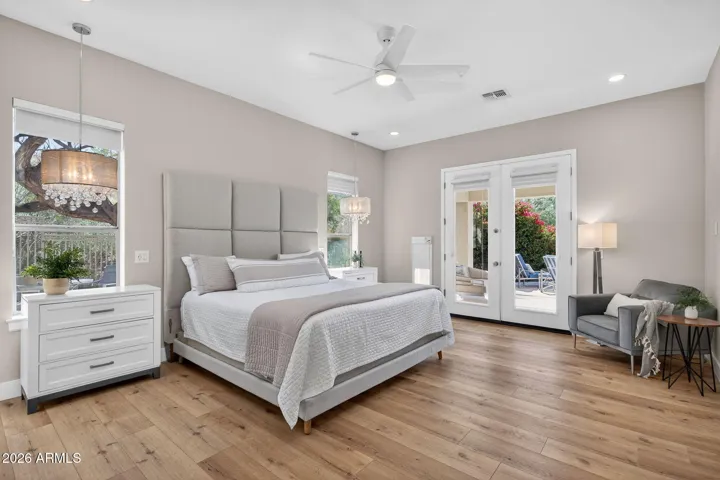 Expansive Scottsdale primary bedroom featuring pendant lights, modern ceiling fan, and private patio access, offering a bright and relaxing retreat with updated finishes.