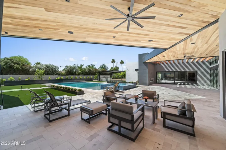 Large back patio with shaded seating, modern architecture, and views of the pool. This Paradise Valley home features a resort-style outdoor space ideal for relaxation.