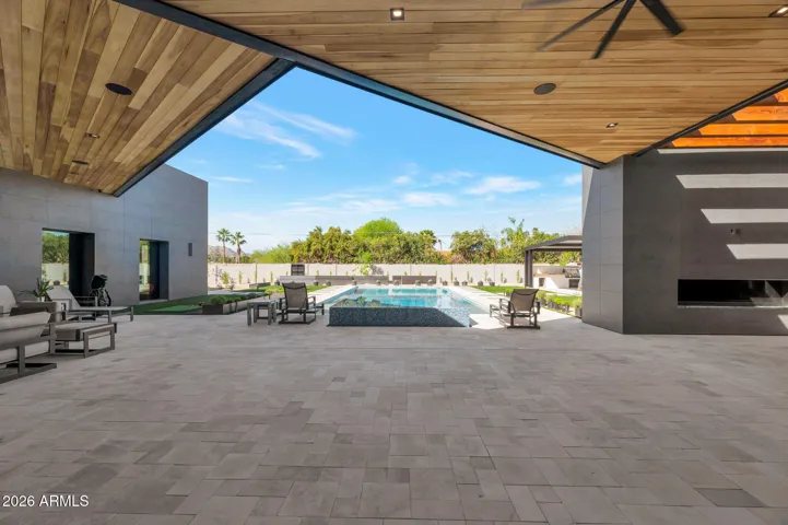 Open patio space leading to a sparkling pool and landscaped yard. This Paradise Valley home highlights seamless outdoor flow and luxury living.