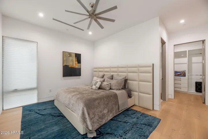Bright fourth bedroom featuring modern finishes, wood flooring, and an open closet system. This Paradise Valley home offers flexible living space ideal for guests or a home office.